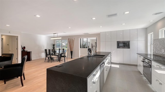 kitchen with sink, white cabinetry, hanging light fixtures, a center island, and built in microwave