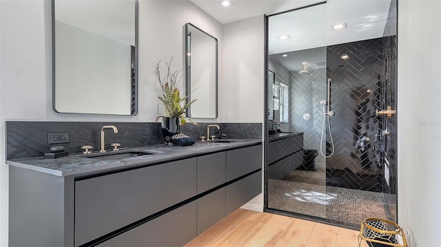 bathroom featuring hardwood / wood-style flooring, tiled shower, and vanity