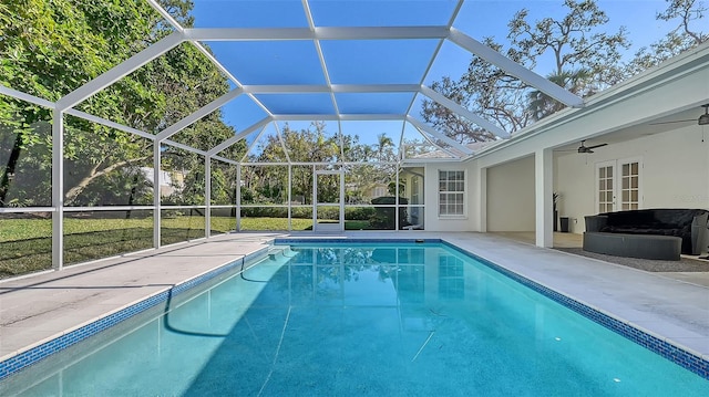 view of swimming pool with ceiling fan, glass enclosure, and a patio area