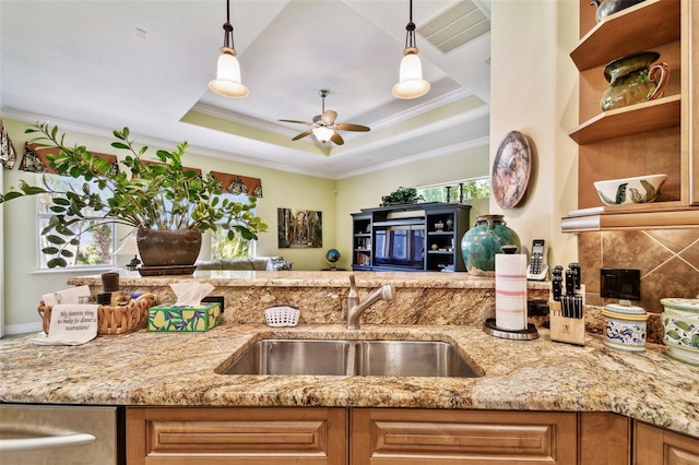 kitchen featuring light stone counters, a tray ceiling, sink, and hanging light fixtures