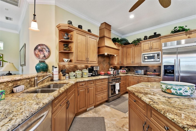 kitchen featuring sink, premium range hood, hanging light fixtures, backsplash, and built in appliances