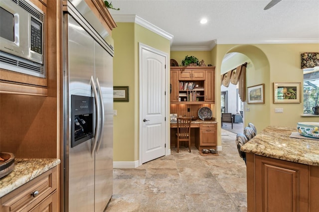 kitchen featuring crown molding, appliances with stainless steel finishes, light stone countertops, and a textured ceiling