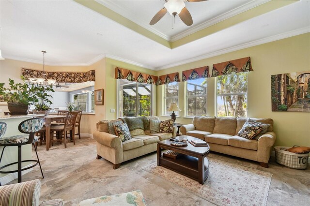 living room with ceiling fan with notable chandelier, ornamental molding, and a raised ceiling