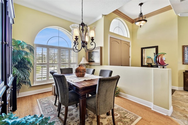 dining space with light hardwood / wood-style flooring, a notable chandelier, crown molding, and a wealth of natural light