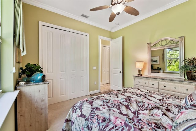 bedroom featuring ceiling fan, ornamental molding, light colored carpet, and a closet