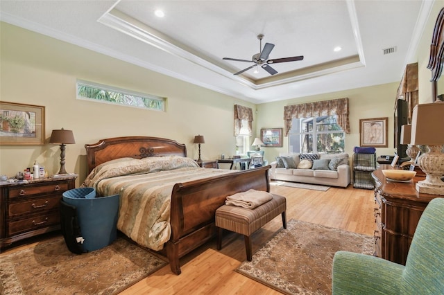 bedroom featuring crown molding, ceiling fan, a raised ceiling, and light hardwood / wood-style flooring