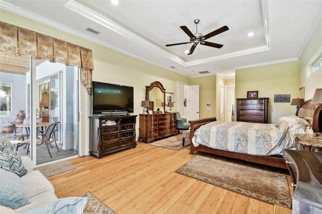 bedroom with crown molding, ceiling fan, a tray ceiling, and light wood-type flooring