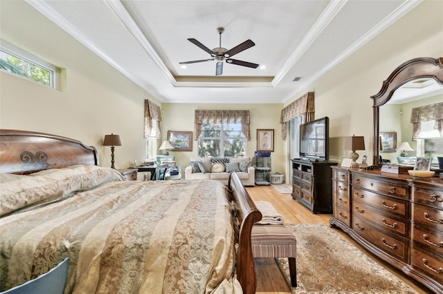 bedroom featuring ceiling fan, ornamental molding, a tray ceiling, and light hardwood / wood-style floors