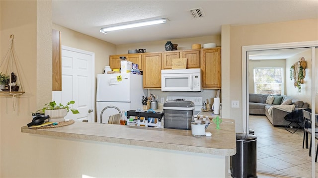 kitchen with sink, light tile patterned floors, a textured ceiling, and white appliances