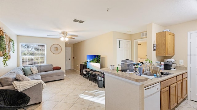 kitchen with dishwasher, sink, light tile patterned floors, ceiling fan, and kitchen peninsula