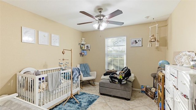 bedroom with light tile patterned floors, a crib, and ceiling fan