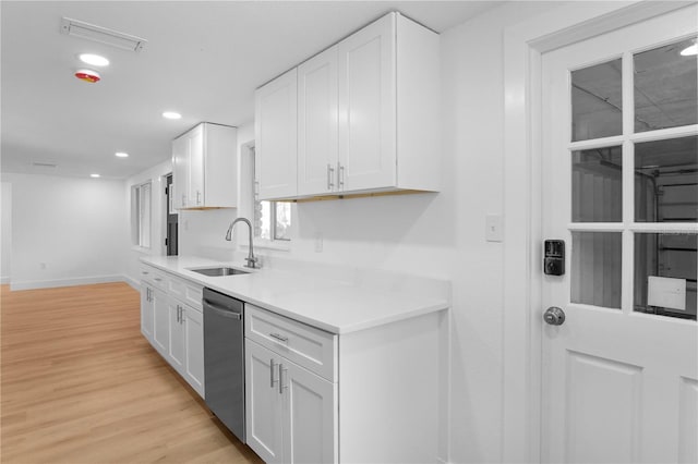 kitchen with white cabinetry, sink, stainless steel dishwasher, and light wood-type flooring