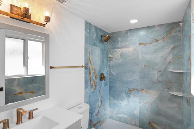 bathroom with vanity, toilet, and a tile shower