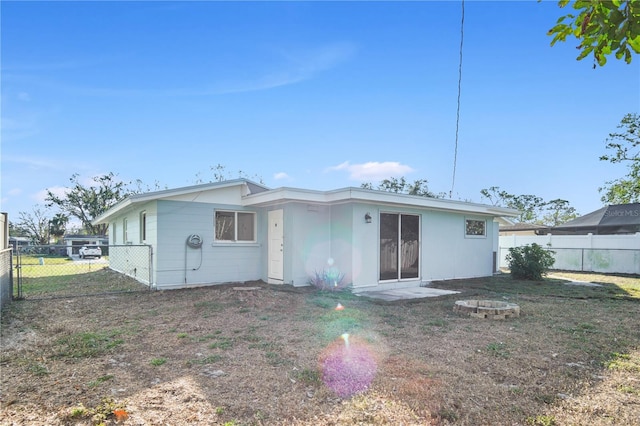 back of property with a yard and a fire pit