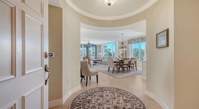 entrance foyer with light tile patterned flooring, ornamental molding, and an inviting chandelier