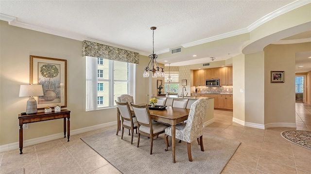 dining area with crown molding, a textured ceiling, a healthy amount of sunlight, and light tile patterned flooring