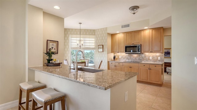 kitchen featuring decorative light fixtures, sink, decorative backsplash, light stone counters, and kitchen peninsula