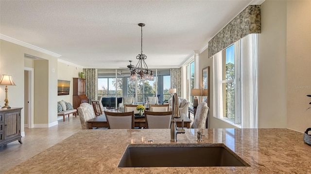 kitchen with sink, hanging light fixtures, ornamental molding, light tile patterned floors, and a textured ceiling