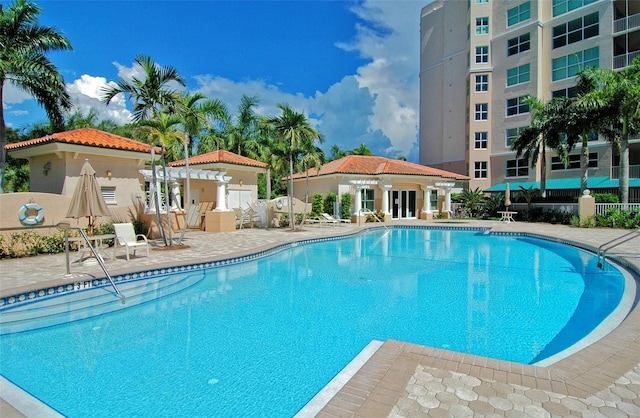 view of swimming pool with a patio, an outdoor structure, and a pergola