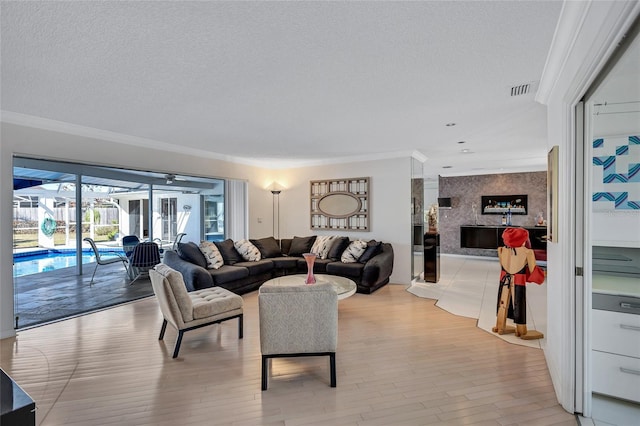 living room with crown molding, a textured ceiling, and light wood-type flooring