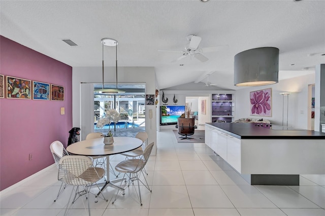 dining room with ceiling fan, lofted ceiling, a textured ceiling, and light tile patterned floors