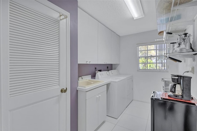 laundry room with sink, cabinets, light tile patterned floors, independent washer and dryer, and a textured ceiling