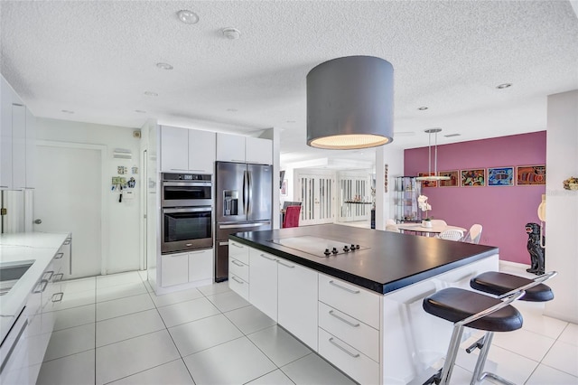 kitchen with white cabinetry, decorative light fixtures, stainless steel appliances, and a kitchen island