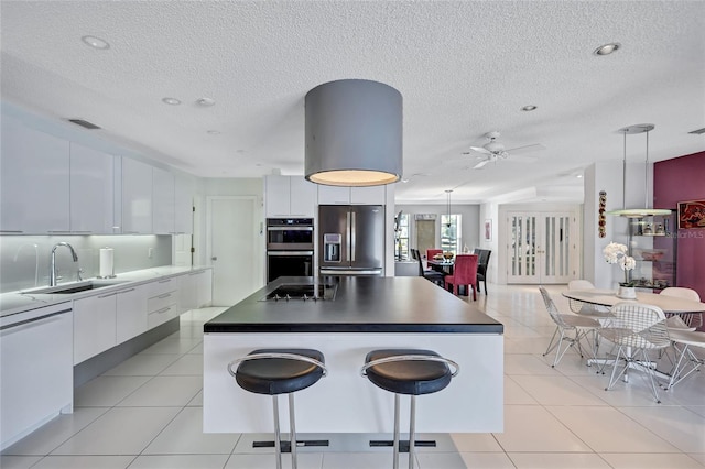 kitchen featuring light tile patterned flooring, white cabinets, hanging light fixtures, a center island, and stainless steel appliances