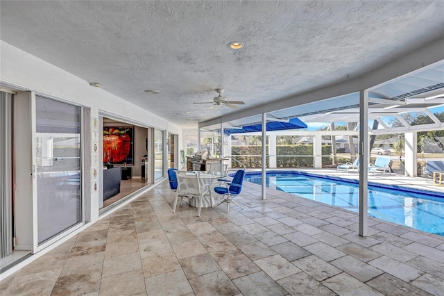 view of pool with a patio, ceiling fan, and glass enclosure