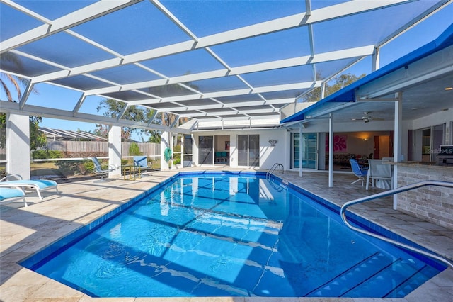 view of swimming pool with a patio, exterior bar, ceiling fan, and glass enclosure