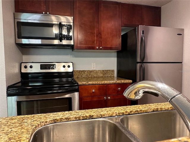 kitchen featuring sink, light stone countertops, and appliances with stainless steel finishes