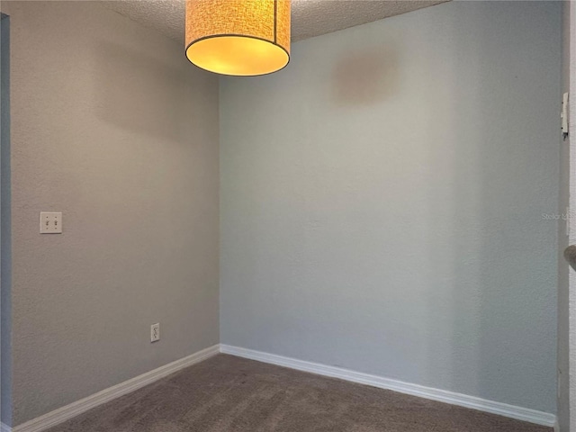 spare room featuring a textured ceiling and dark colored carpet