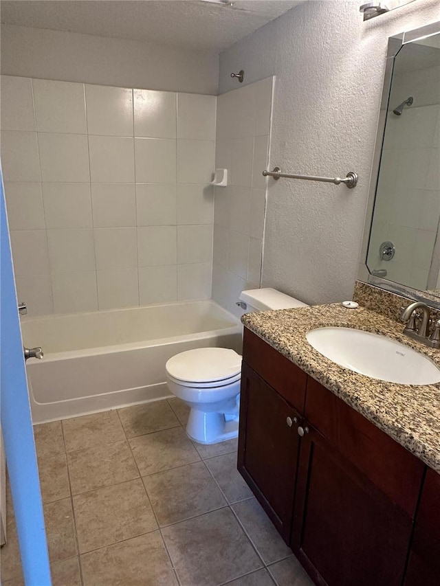 full bathroom with vanity, a textured ceiling, tile patterned floors, toilet, and tiled shower / bath