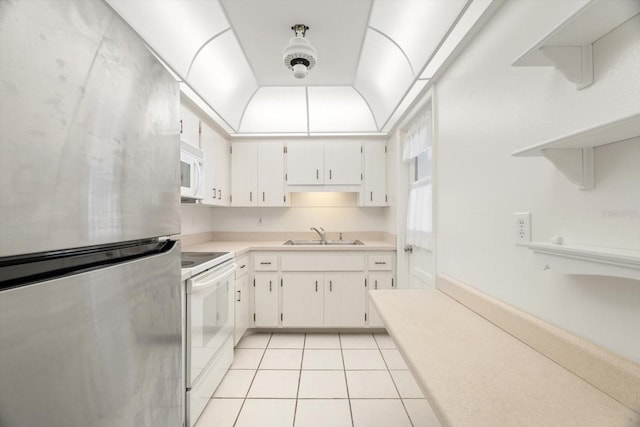 kitchen with sink, light tile patterned floors, white cabinets, and white appliances