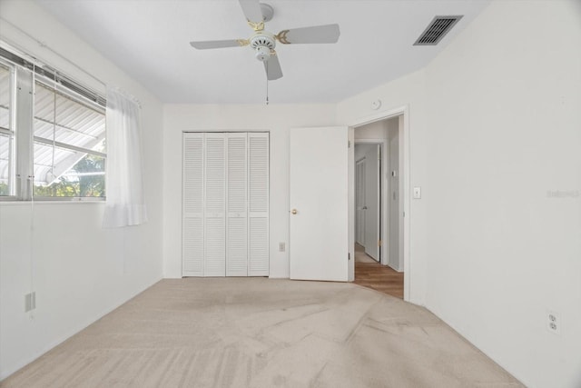 unfurnished bedroom with light colored carpet, a closet, and ceiling fan