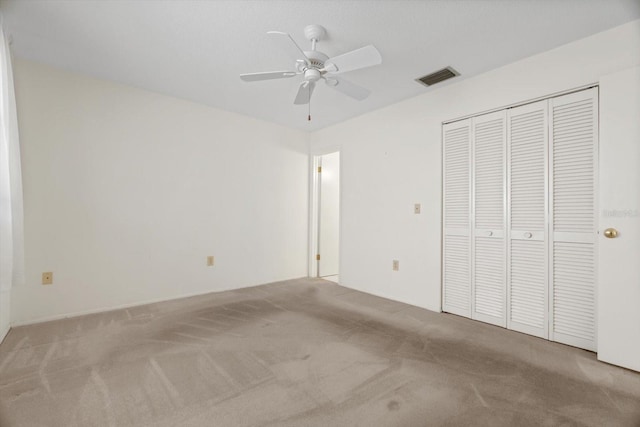 unfurnished bedroom featuring ceiling fan, light colored carpet, and a closet