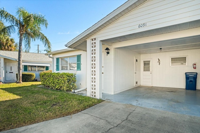 property entrance with a yard and a carport