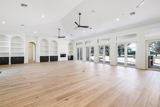 unfurnished living room featuring built in shelves, ceiling fan, high vaulted ceiling, and light hardwood / wood-style floors