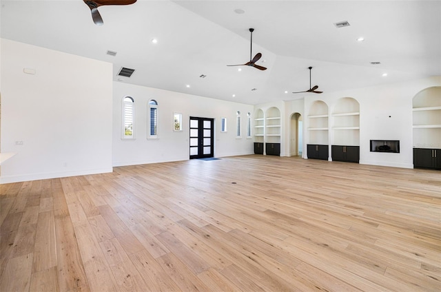 unfurnished living room with high vaulted ceiling, built in features, ceiling fan, and light hardwood / wood-style floors