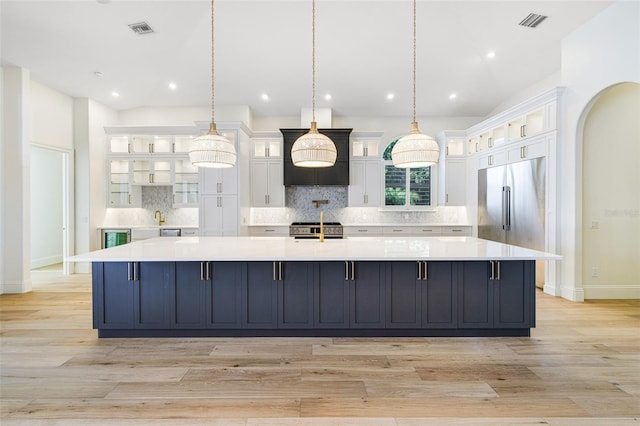 kitchen with a large island with sink, white cabinetry, and decorative light fixtures