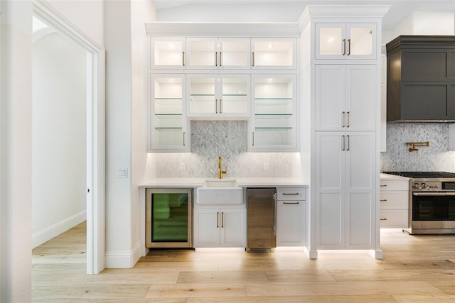 kitchen featuring white cabinets, stainless steel stove, and beverage cooler