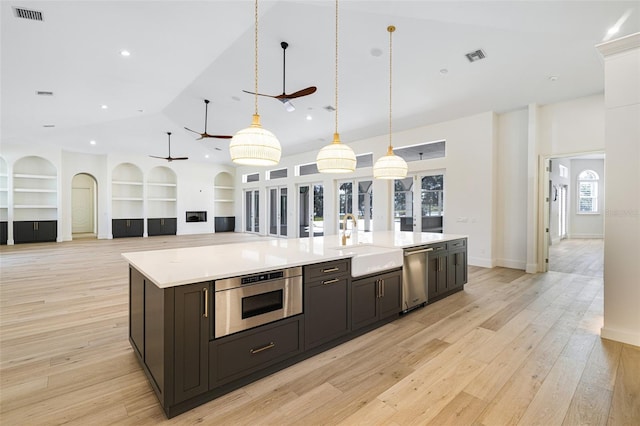 kitchen with sink, appliances with stainless steel finishes, built in features, pendant lighting, and a large island