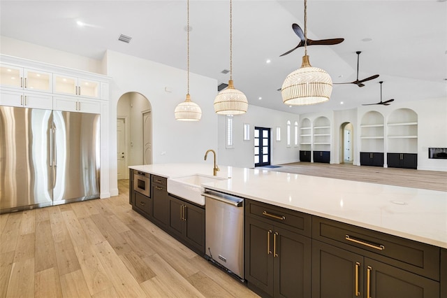 kitchen featuring decorative light fixtures, sink, white cabinets, light hardwood / wood-style floors, and stainless steel appliances