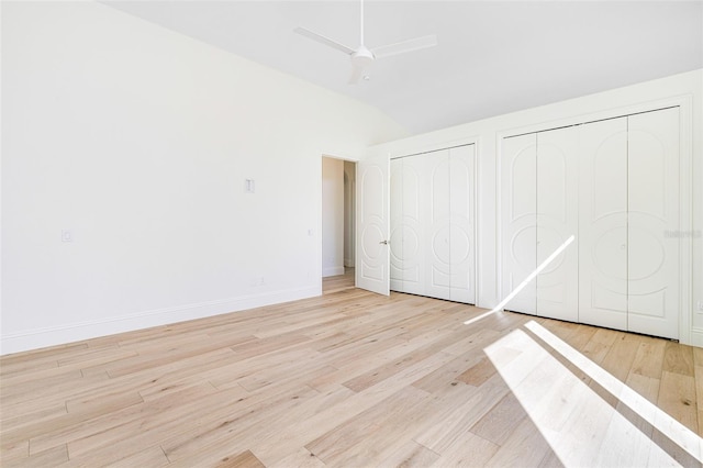 unfurnished bedroom featuring multiple closets, ceiling fan, lofted ceiling, and light wood-type flooring