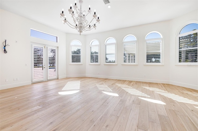 spare room featuring a notable chandelier and light wood-type flooring