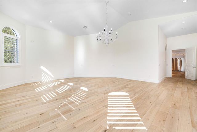 empty room featuring lofted ceiling, a notable chandelier, and light hardwood / wood-style flooring