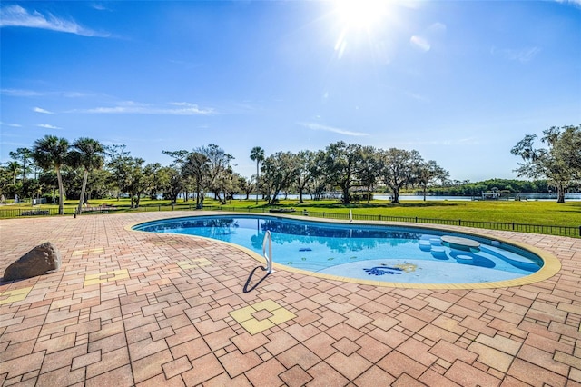 view of swimming pool featuring a patio, a water view, and a yard