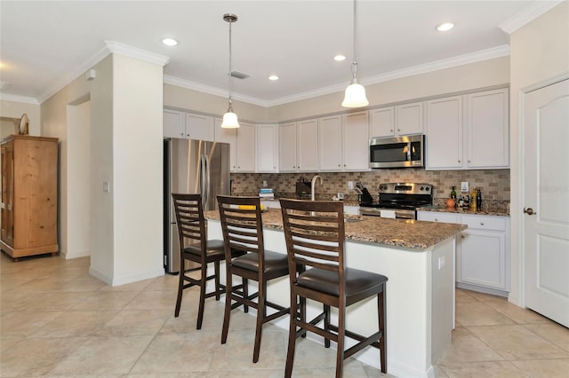 kitchen with a breakfast bar area, appliances with stainless steel finishes, dark stone countertops, an island with sink, and decorative light fixtures