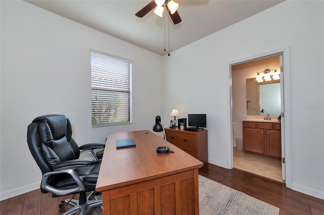 home office featuring dark wood-type flooring, sink, and ceiling fan