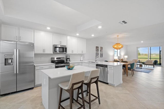 kitchen featuring sink, white cabinetry, hanging light fixtures, appliances with stainless steel finishes, and kitchen peninsula